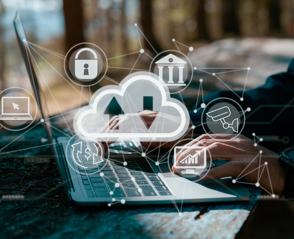 A guy works on a laptop while holding a cloud computing diagram. Data storage, networking, and internet service principles are all based on cloud technology.